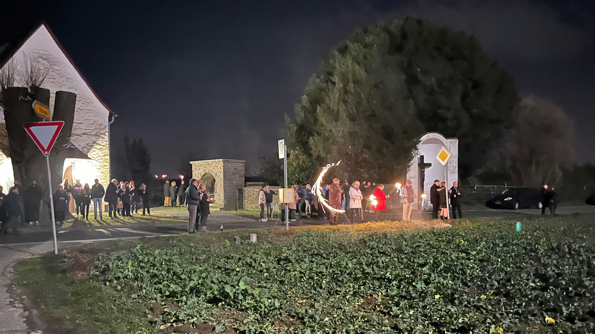 Menschenansammlung bei der Kapelle am Feld. Vereinzeltes Feuerwerk ist zu sehen.