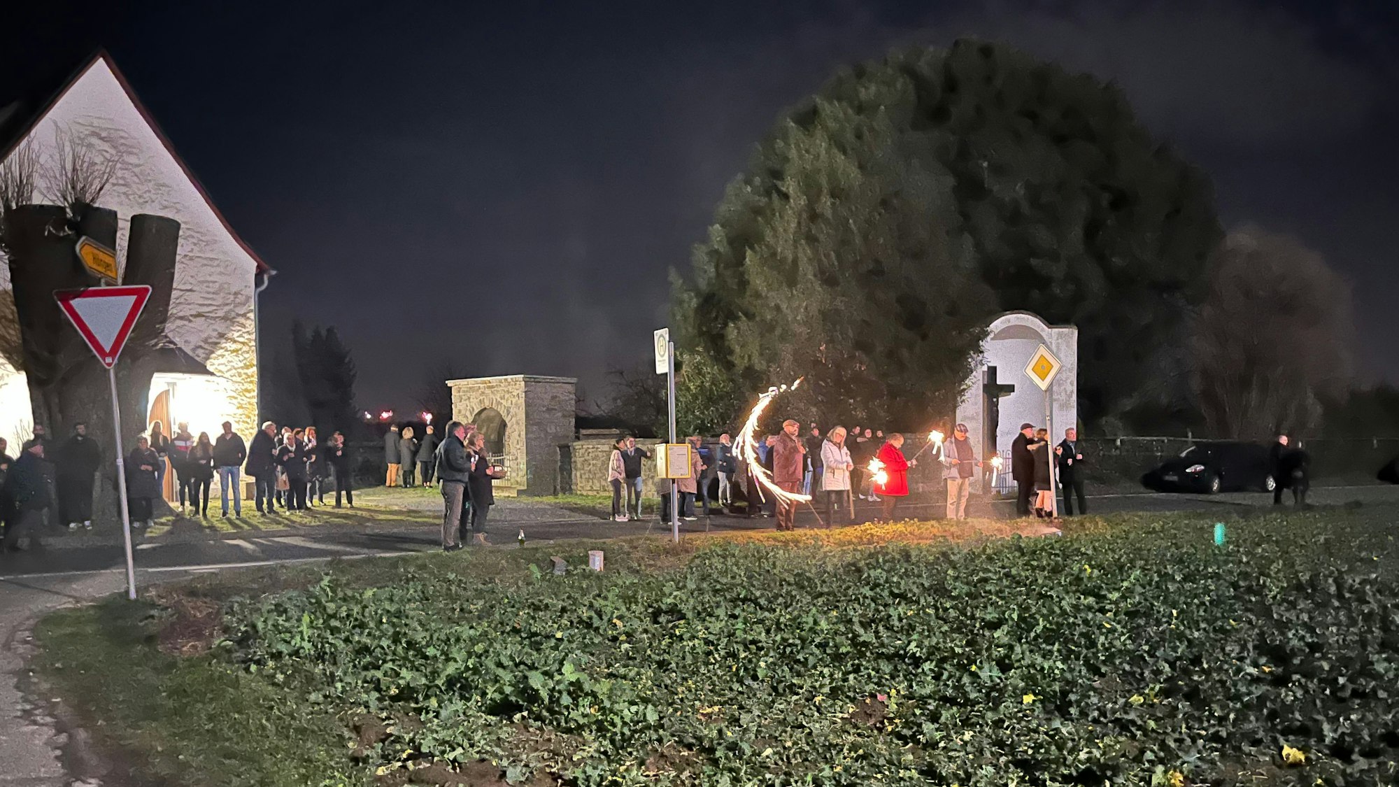 Menschenansammlung bei der Kapelle am Feld. Vereinzeltes Feuerwerk ist zu sehen.