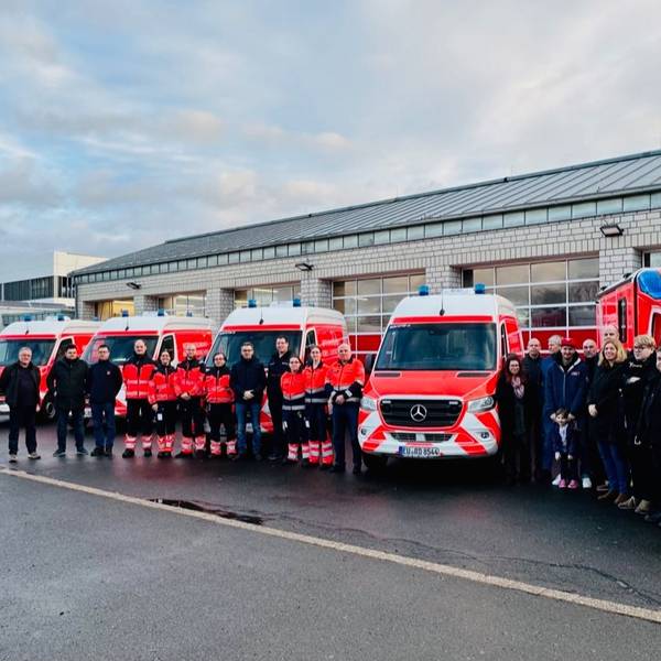 Die Mitarbeiter nehmen fünf neue Fahrzeuge des Rettungsdienstes in Empfang.
