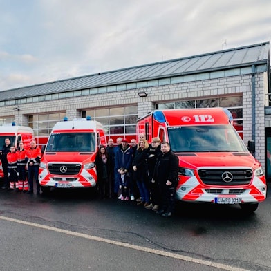 Die Mitarbeiter nehmen fünf neue Fahrzeuge des Rettungsdienstes in Empfang.