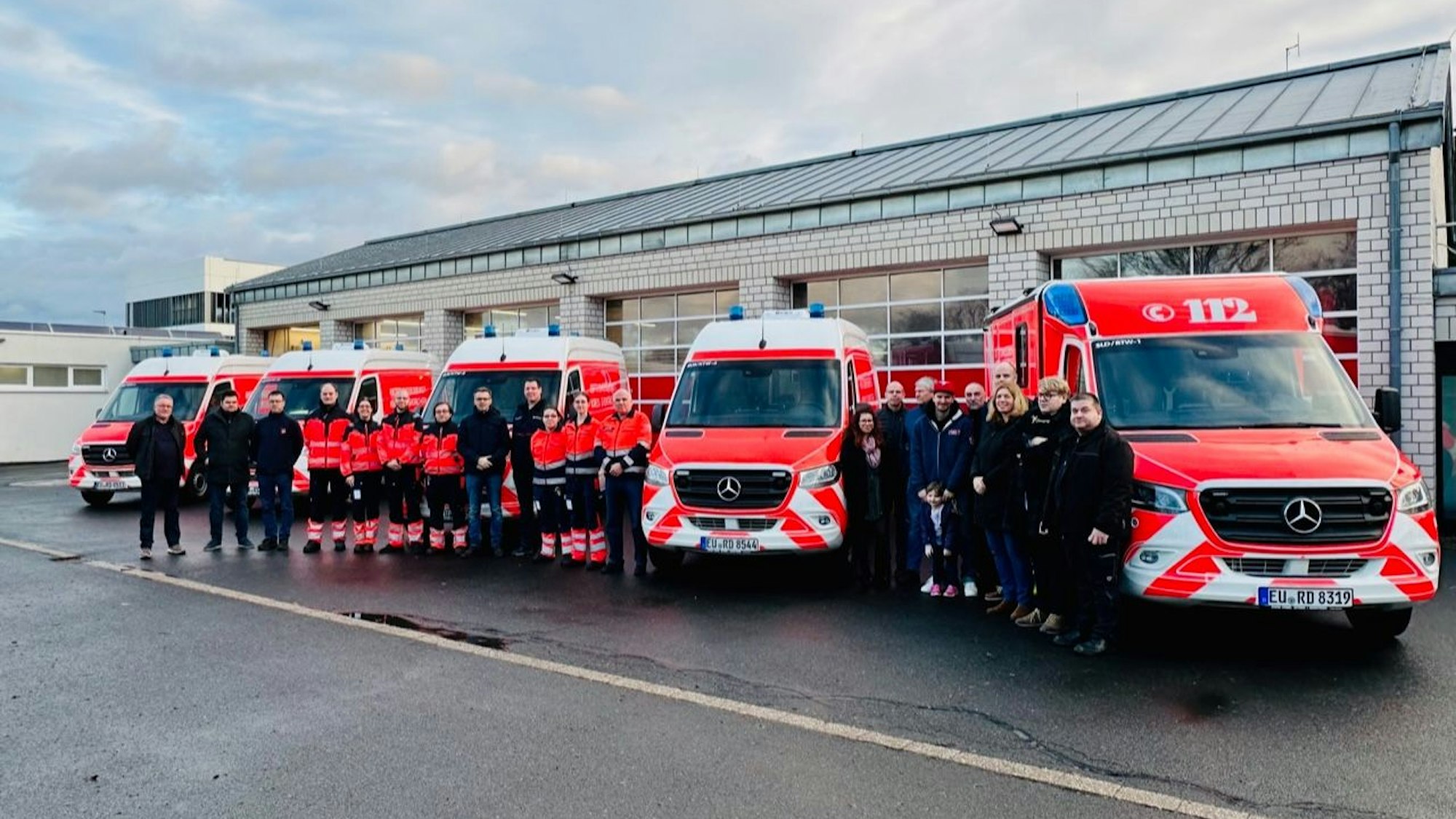 Die Mitarbeiter nehmen fünf neue Fahrzeuge des Rettungsdienstes in Empfang.