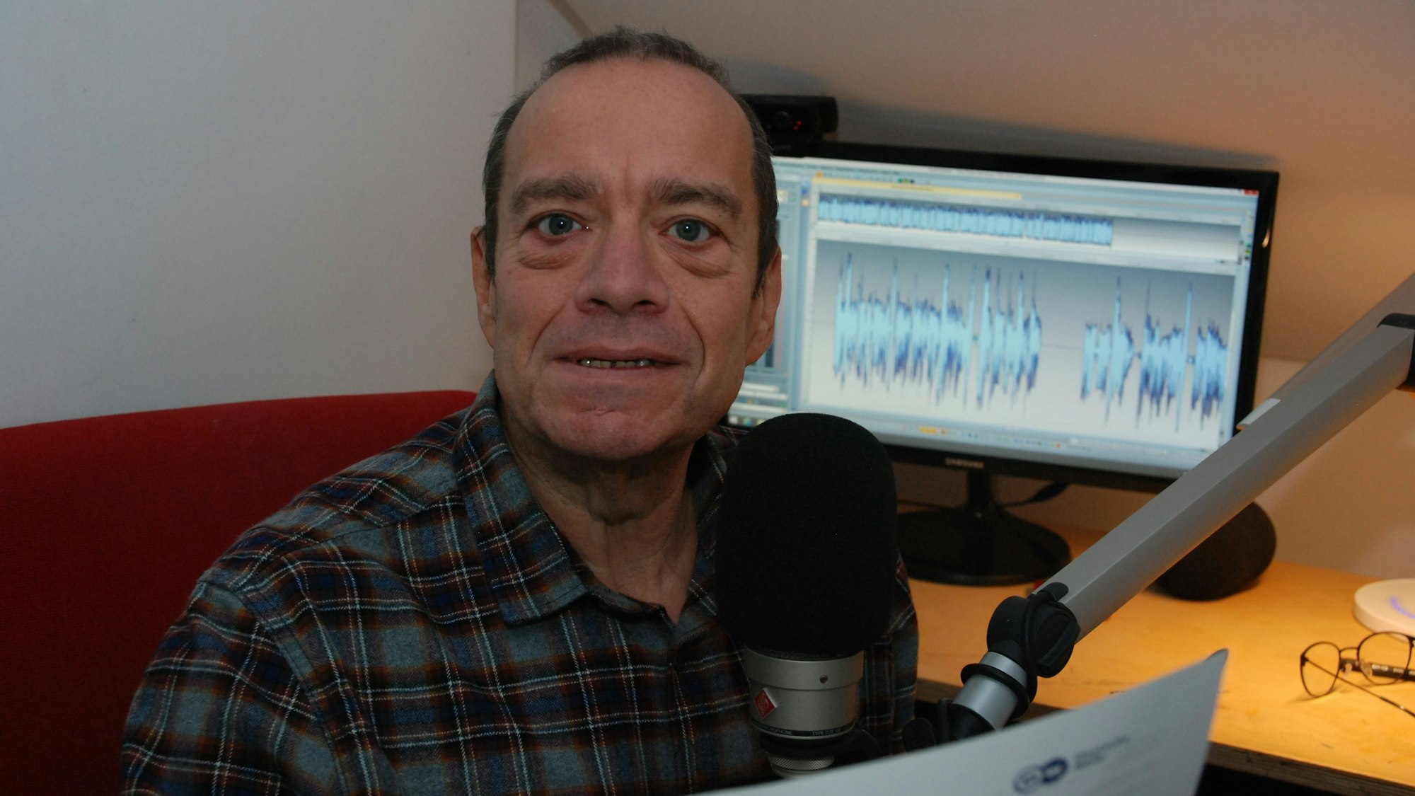 Kaiser vor Mikrofon und Bildschirm in einer Schräge.