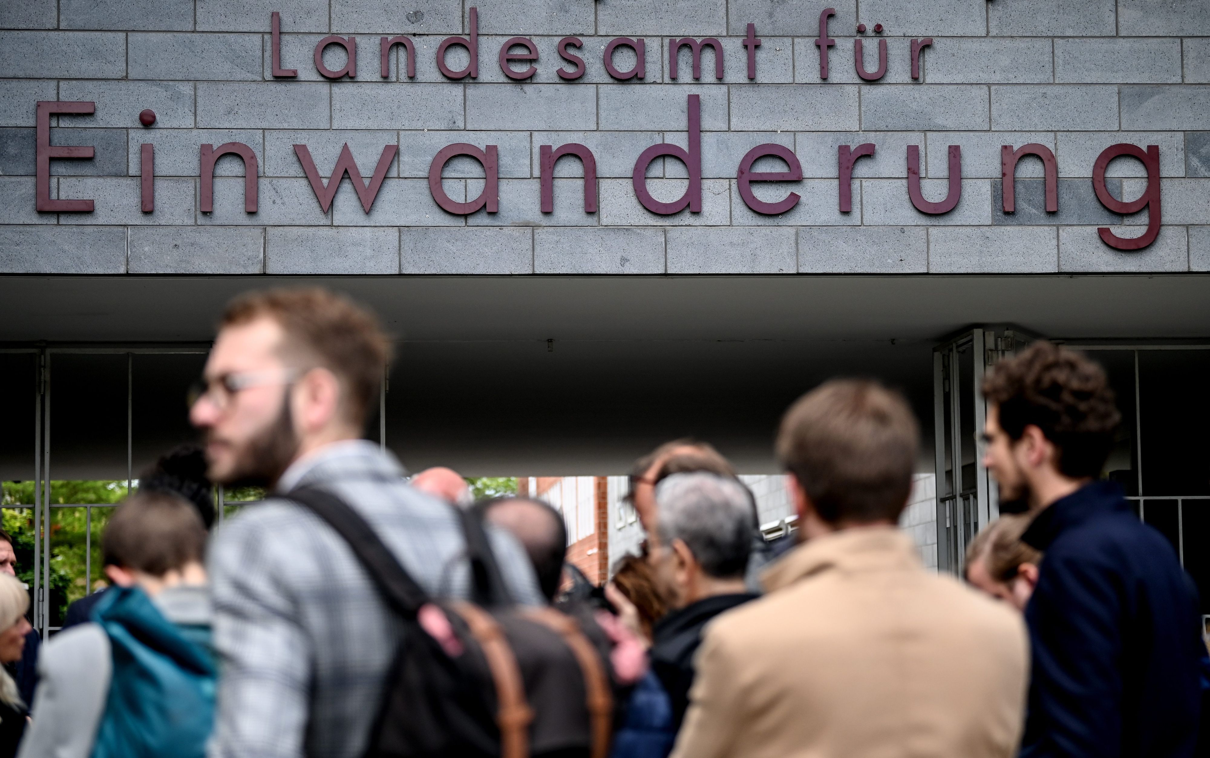 Menschen stehen vor dem Berliner Landesamt für Einwanderung in Berlin