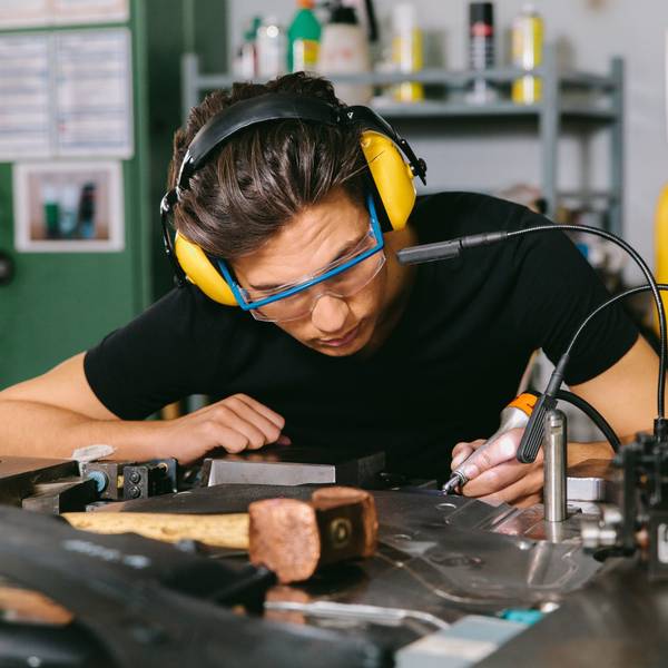 Ein Techniker mit Gehörschutz und Schutzbrille bei der Arbeit.