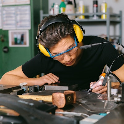 Ein Techniker mit Gehörschutz und Schutzbrille bei der Arbeit.