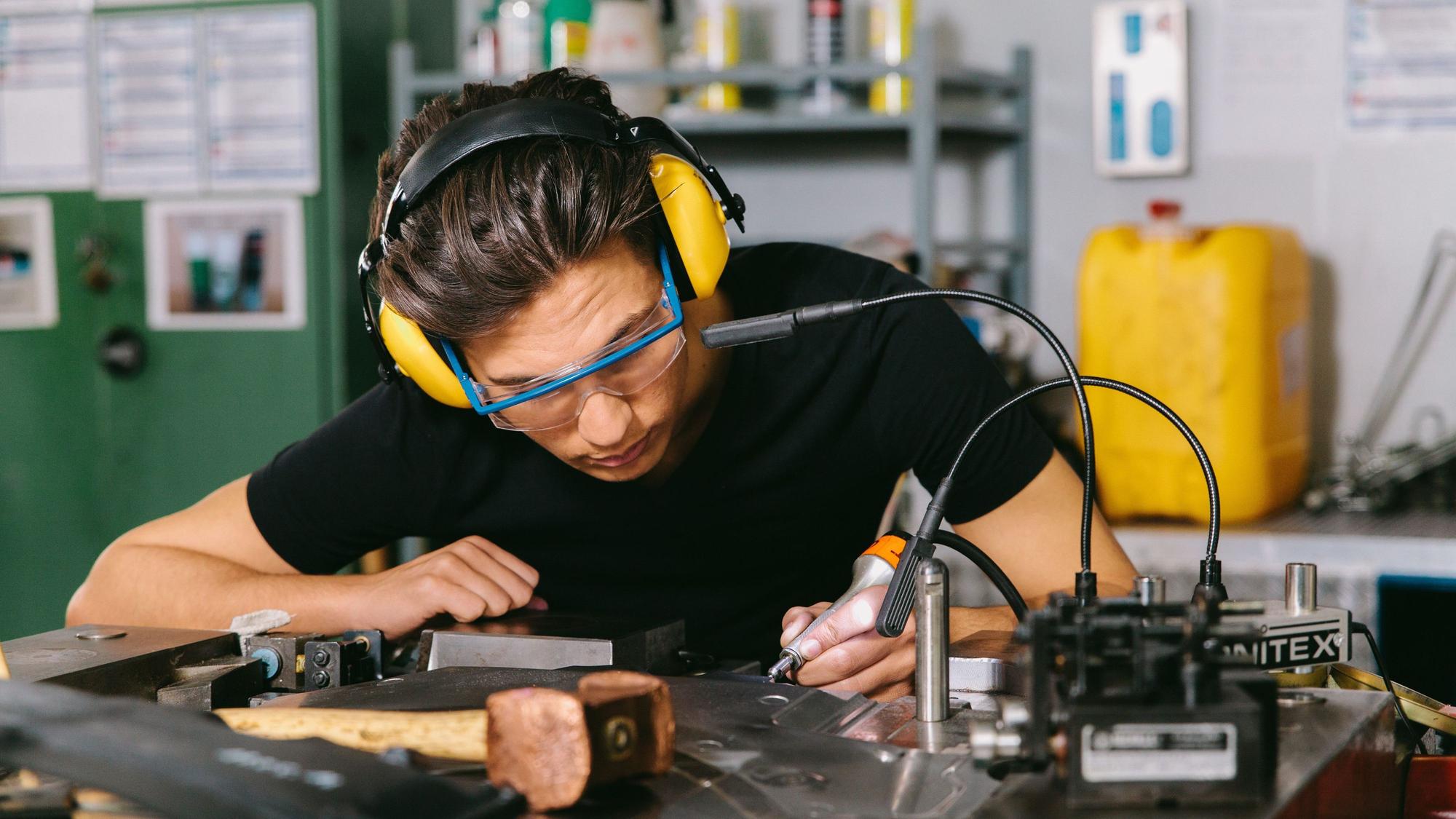 Ein Techniker mit Gehörschutz und Schutzbrille bei der Arbeit.