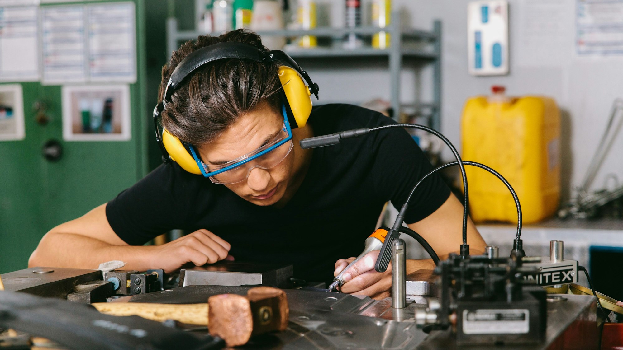 Ein Techniker mit Gehörschutz und Schutzbrille bei der Arbeit.