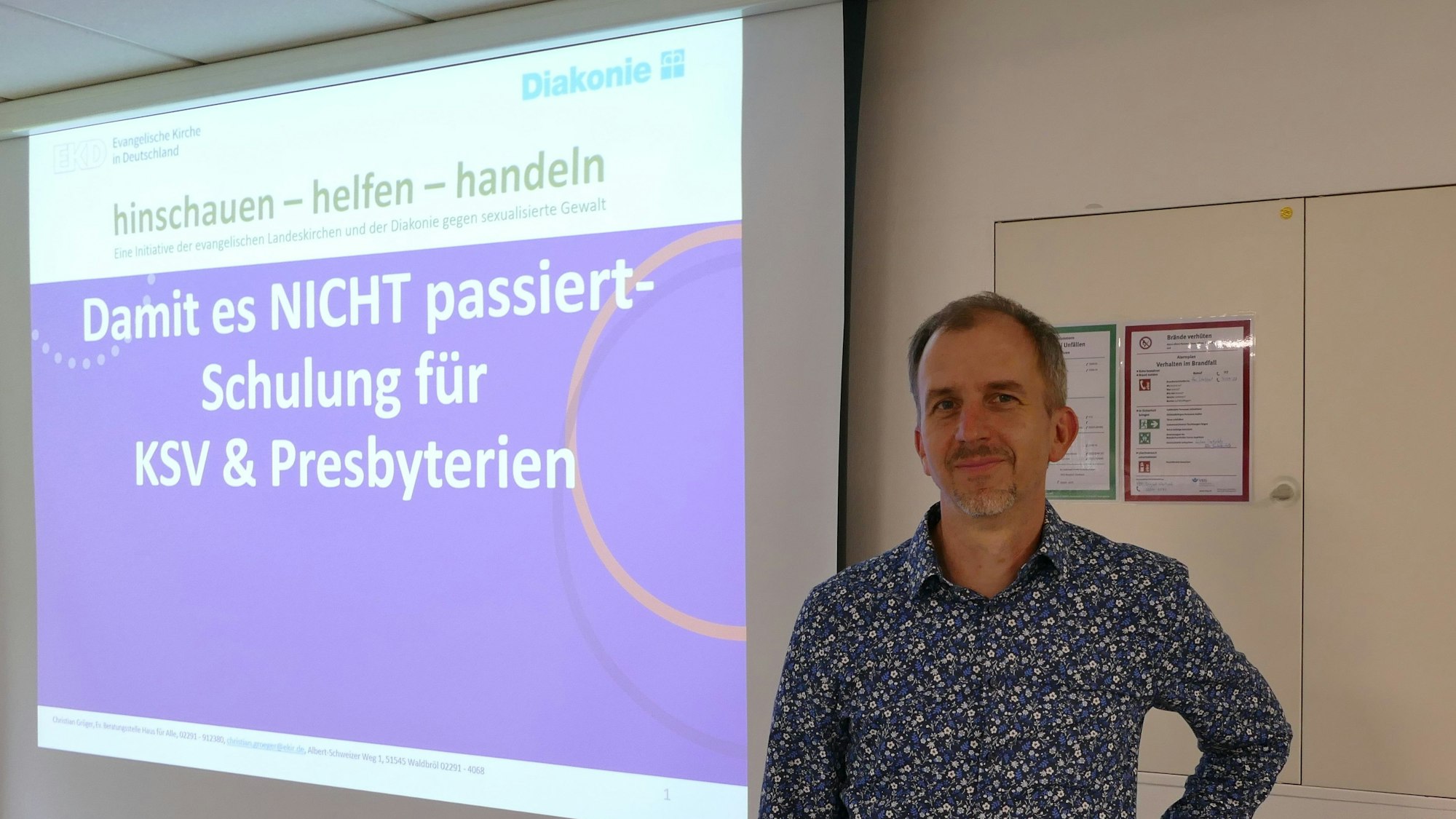 Christian Gröger steht vor einer Leinwand, an die projiziert steht: „Damit es NICHT passiert – Schulung für KSV & Presbyterien“.