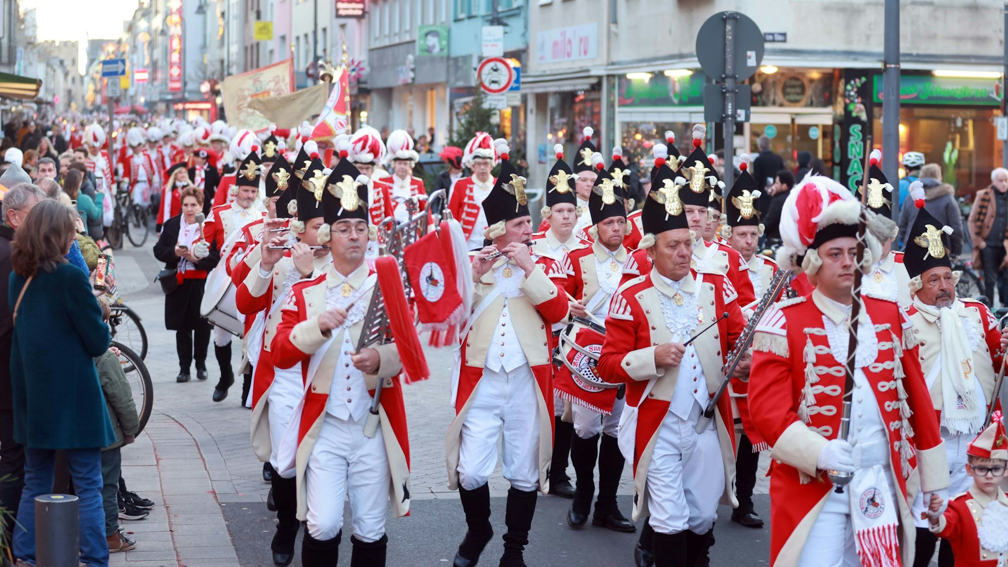 Mitglieder der Roten Funken ziehen mit einem Spielmannszug über die Severinstraße.