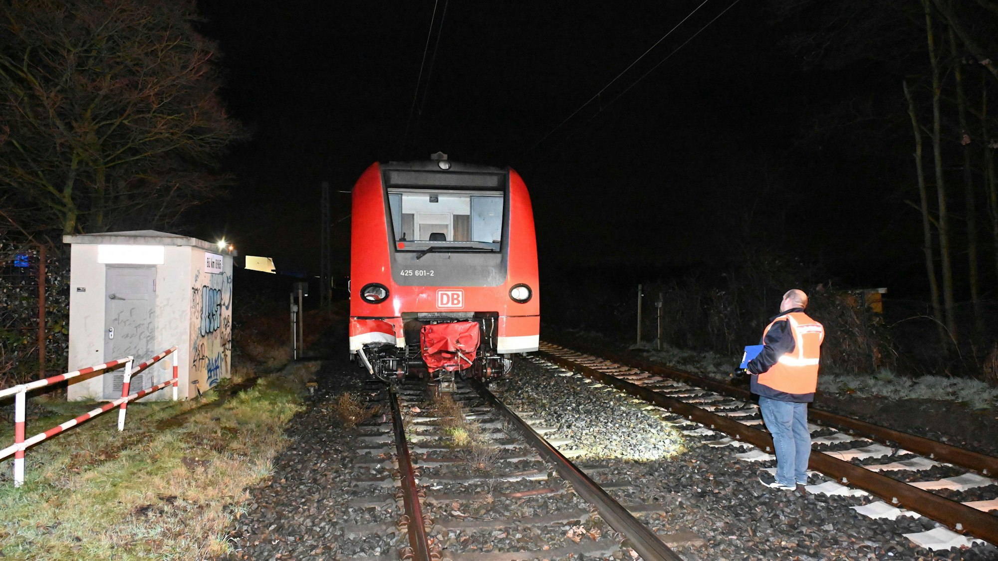 Ein Bahnmitarbeiter steht im Gleisbett, neben ihm steht der Zug, der zuvor die zwei Pferde überrollt hat.