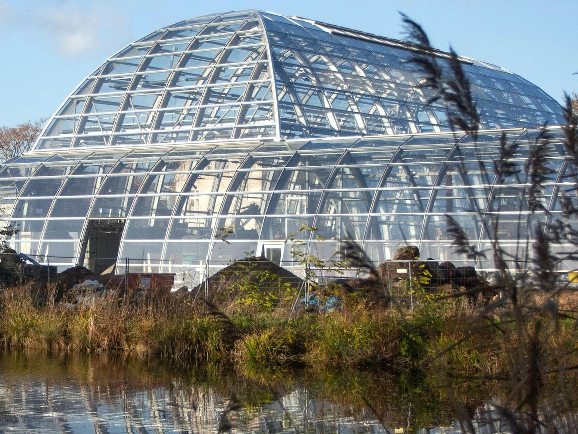 Das Stahlskelett der rampenförmigen Häuser siegelt sich im Wasser des davorliegenden Sees.