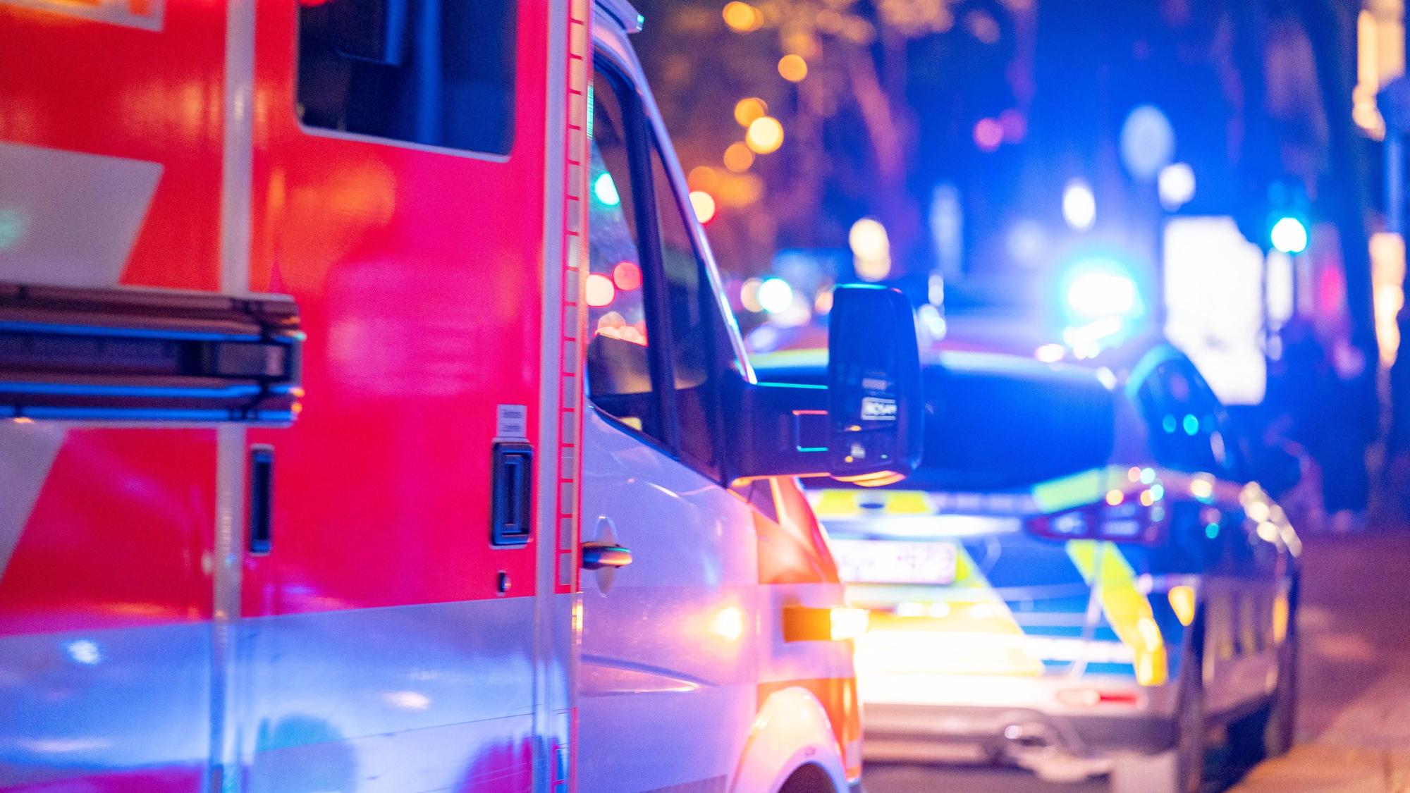 Ein Rettungs- und ein Polizeiwagen sind im Einsatz und stehen auf einer Straße, ihr Blaulicht ist eingeschaltet.