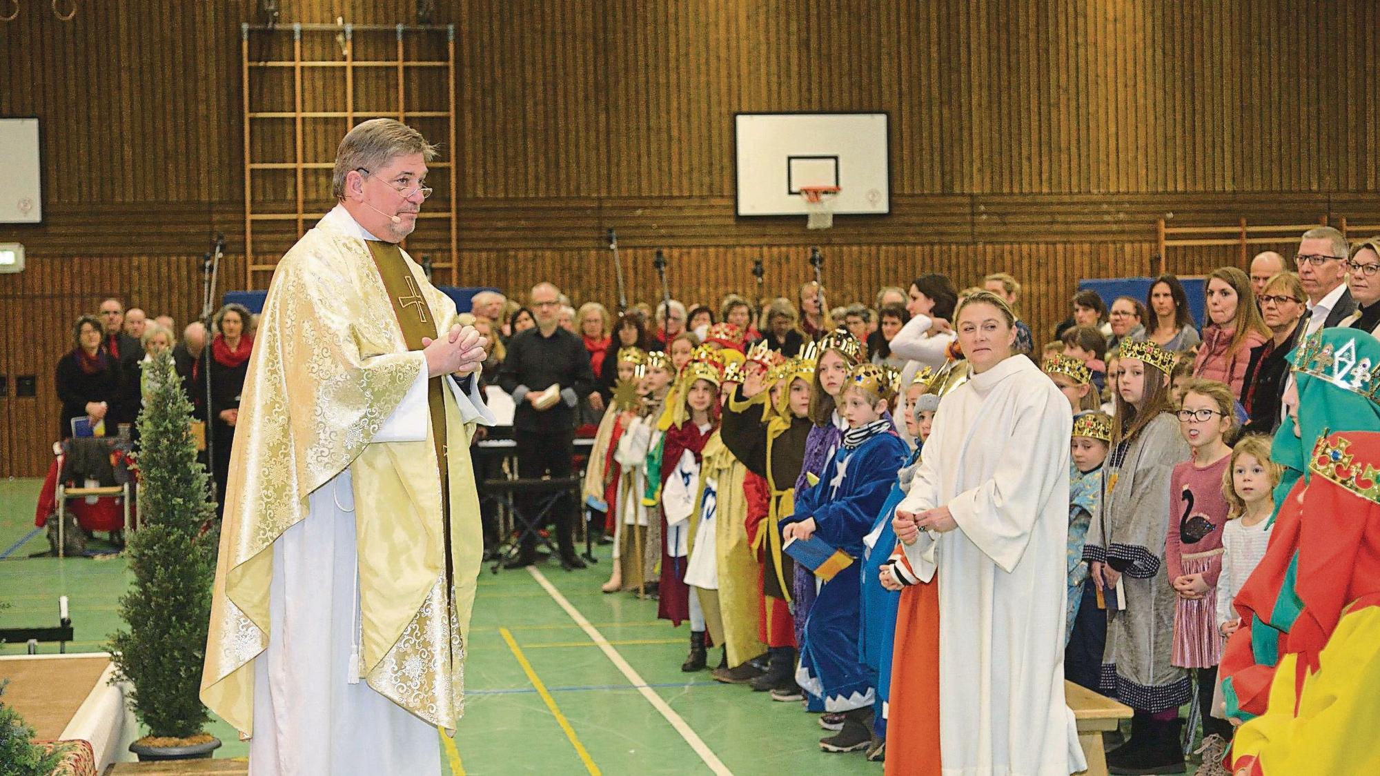 Pastro Harald Fischer steht in einer Kürtener Turnhalle vor Hunderten Menschen.