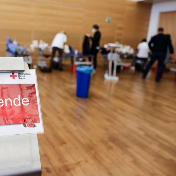 Ein Schild mit der Aufschrift „Blutspende“. Im Hintergrund sind mehrere Liegen aufgebaut.