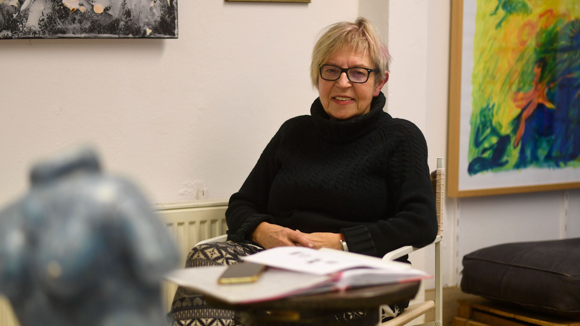 Anne Berger sitzt an einem Tisch in ihrem Kleinen Kunstraum.