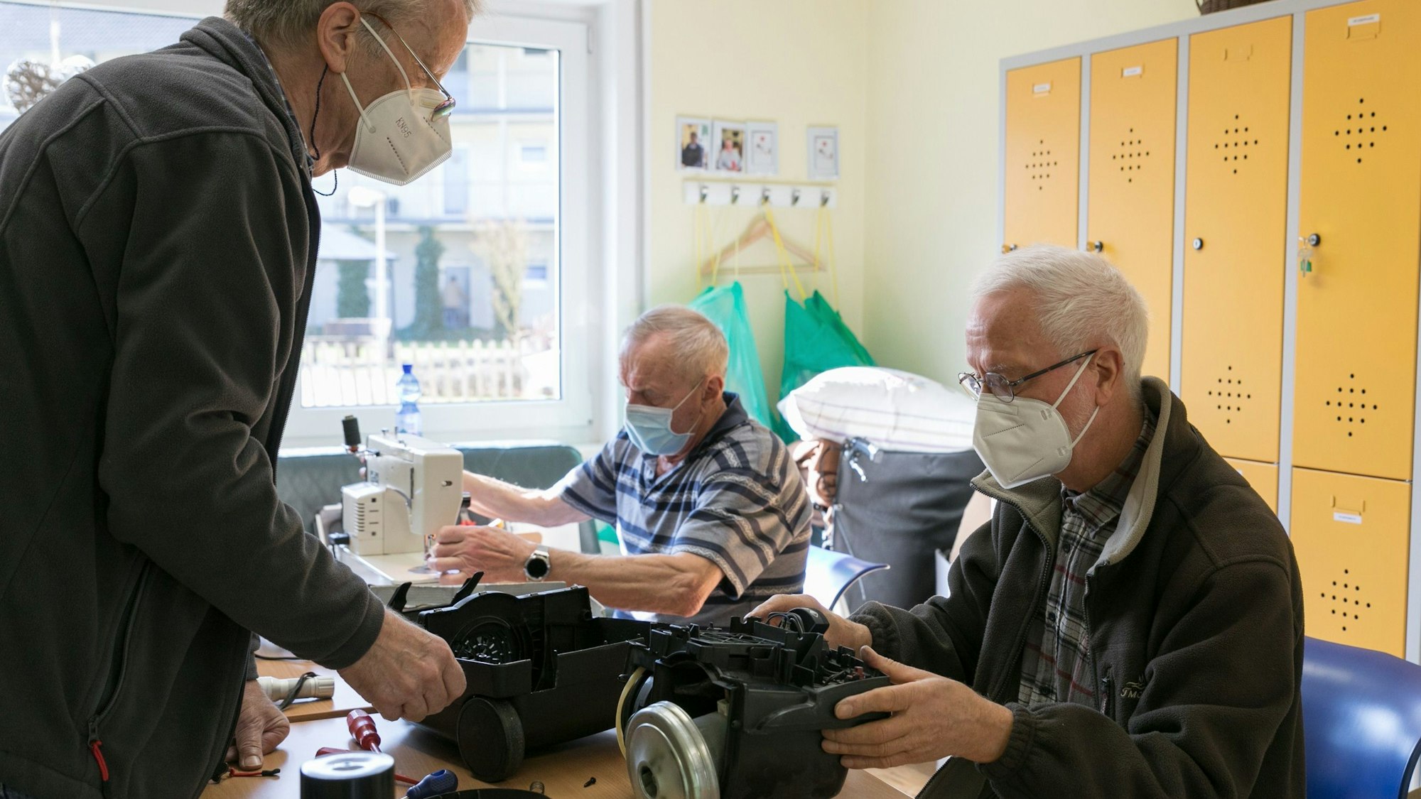 Blick auf zwei Männer, die technische Geräte reparieren.