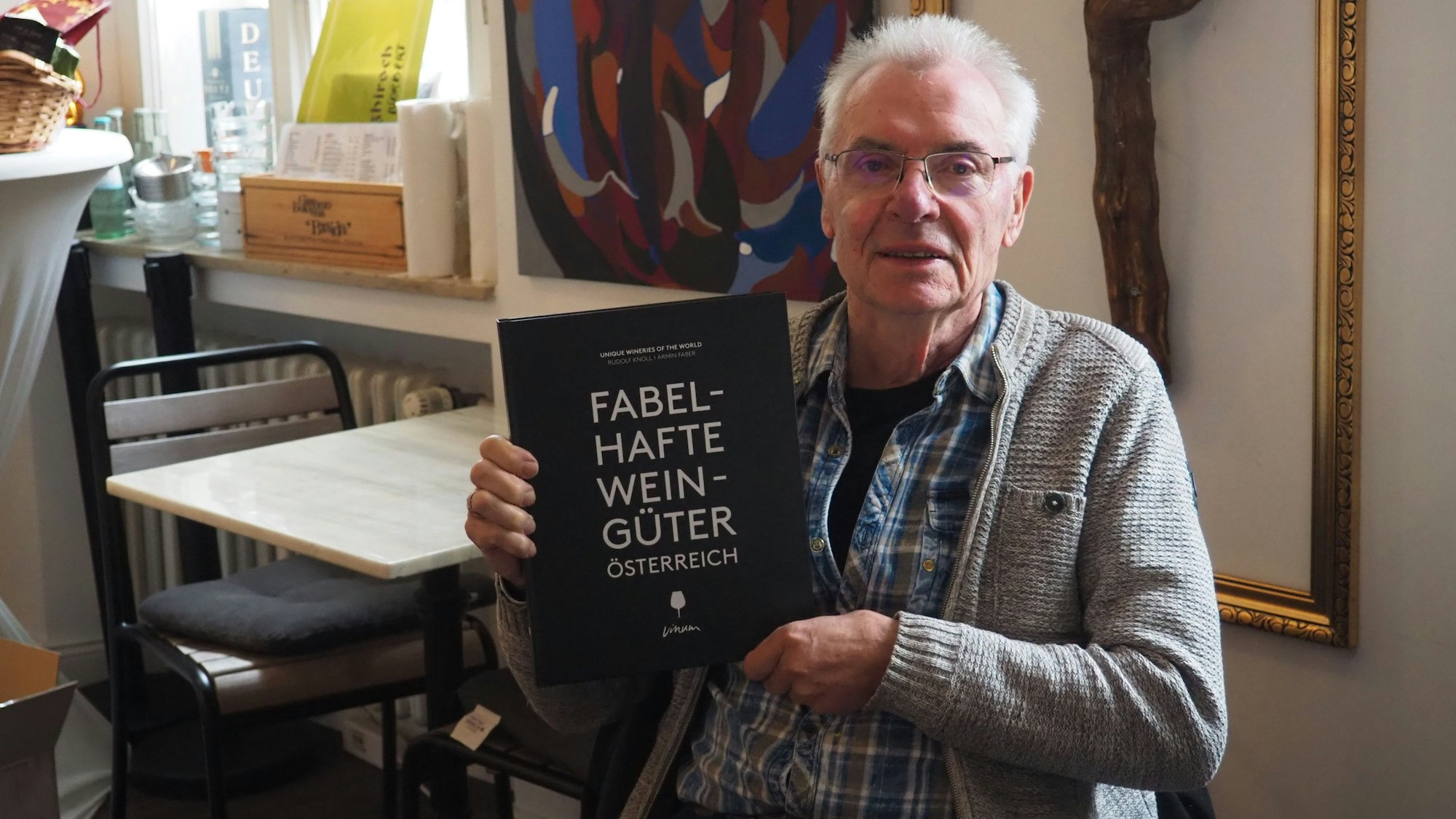 Armin Faber hält das Buch „Fabelhafte Weingüter Österreich“ in der Hand.