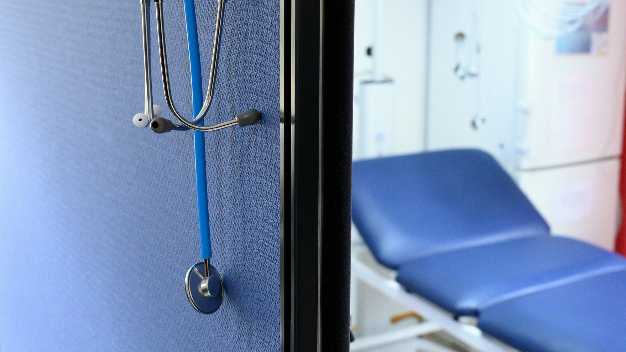 Stethoskope hängen im Behandlungszimmer einer Hausarztpraxis über einer Trennwand.