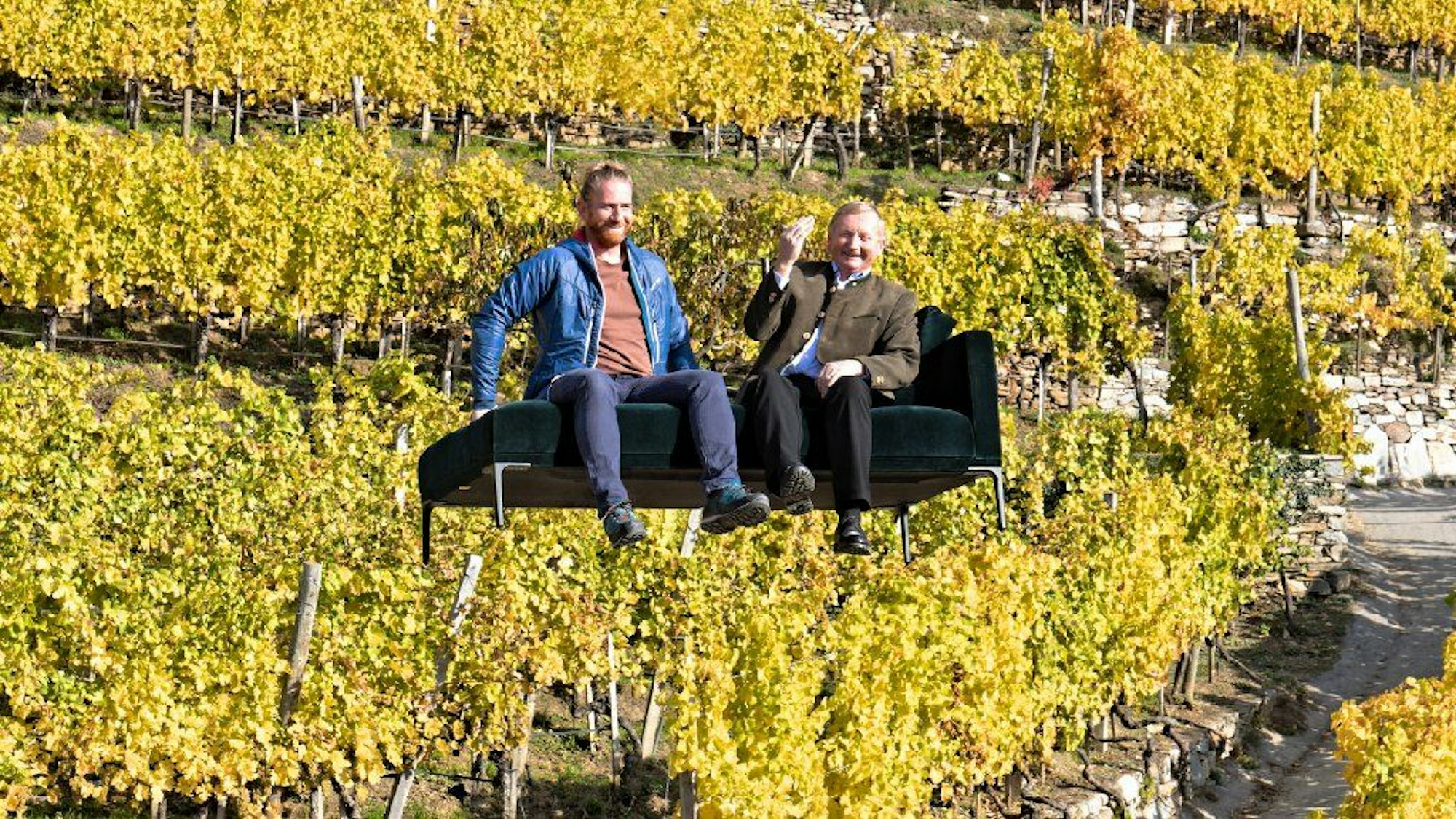 Zwei Menschen sitzen auf einem Sofa, das vor einem Weinberg schwebt.