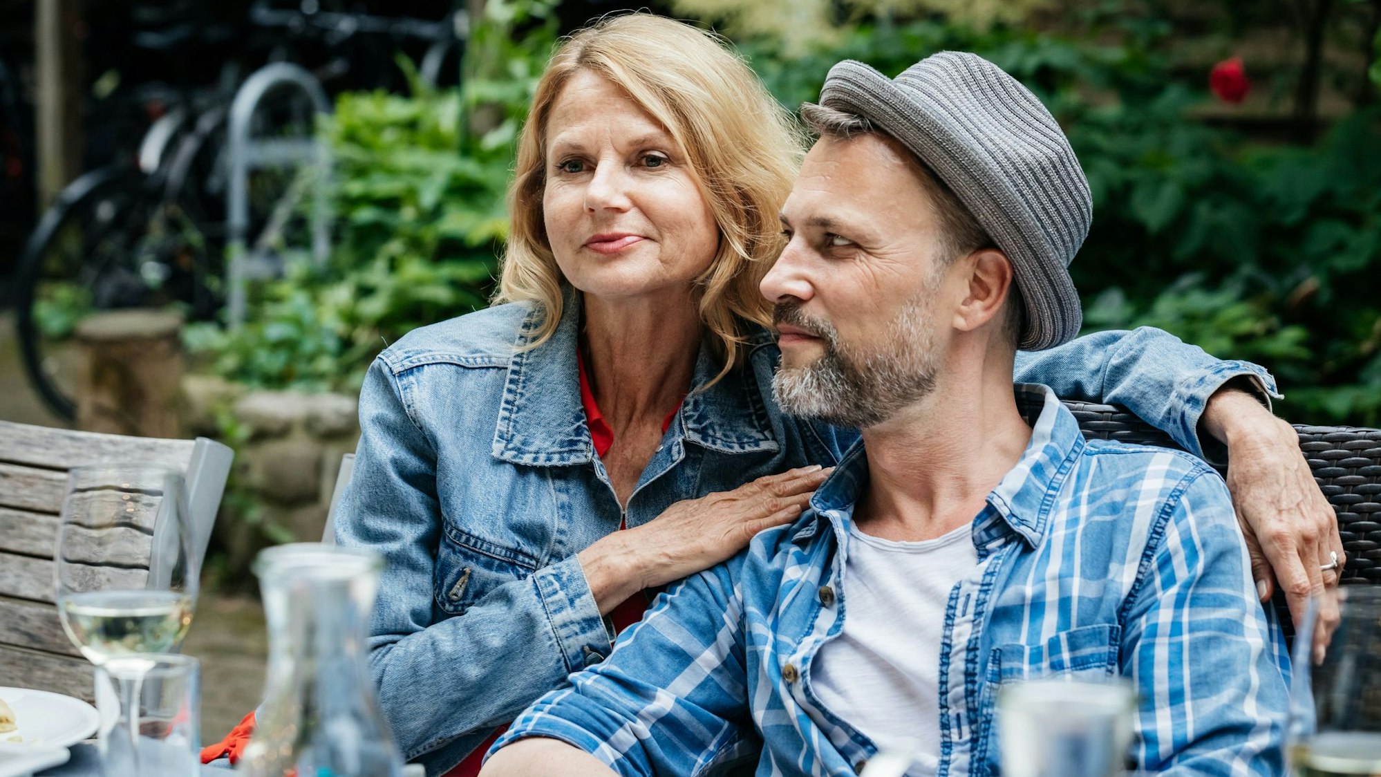 Ein Paar mittleren Alters sitzt bei einem Grillfest nah beieinander.