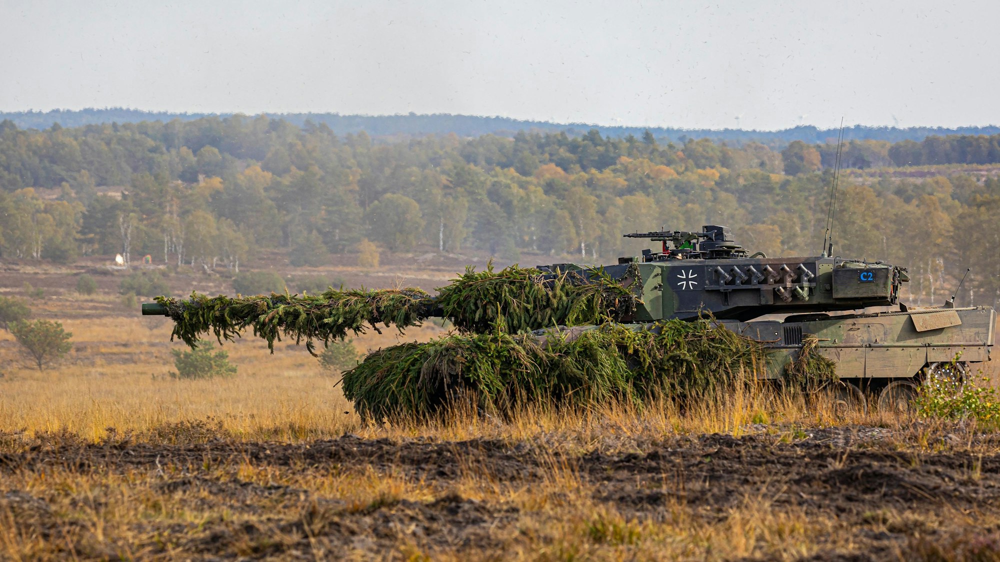 Ein Kampfpanzer Leopard 2 fährt auf einem Feld.