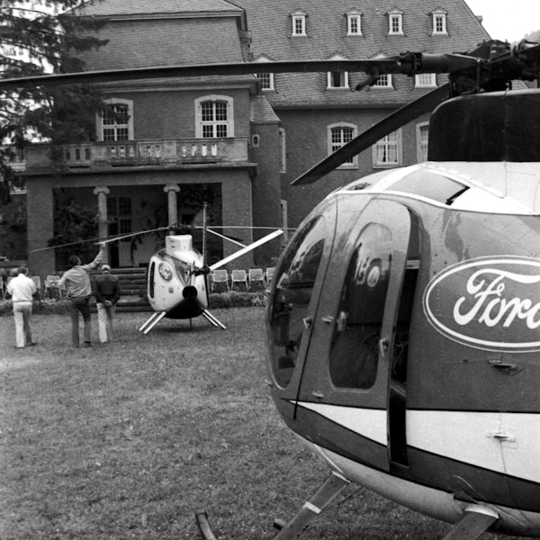 Zwei Hubschrauber mit Ford-Logos steht vor der Burg Dalbenden, daneben drei von der Kamera abgewandte Personen. Das Foto ist in schwarz-weiß.