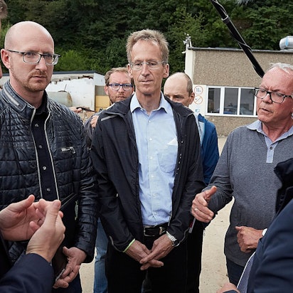 Drei Männer stehen mit ernsten Mienen zusammen.