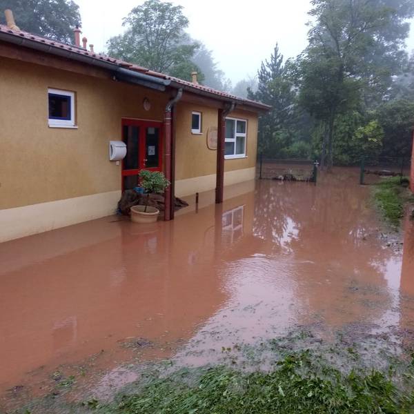 Ein ockerfarbenes Gebäude ist umgeben von rot-braunem Wasser. Im Hintergrund sind Bäume zu erkennen.