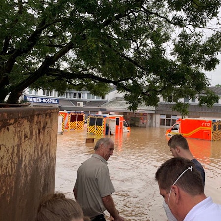 Ein Krankenhaus und mehrere Rettungswagen stehen unter Wasser.