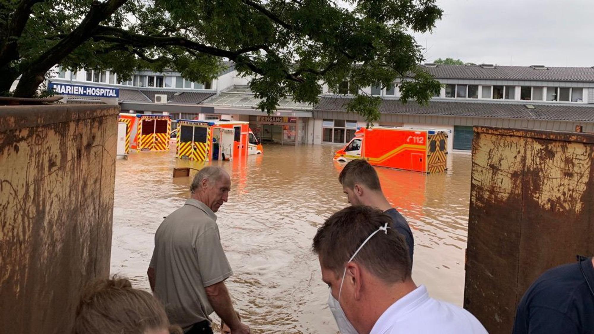 Ein Krankenhaus und mehrere Rettungswagen stehen unter Wasser.
