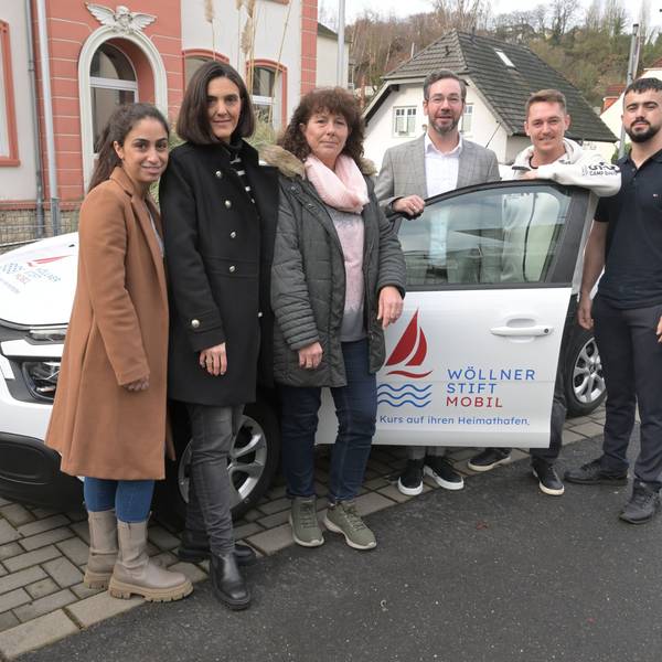 Das Team des Wöllner-Stifts steht in Rösrath-Hoffnungsthal vor dem weißen Wöllner-Stift-Mobil.