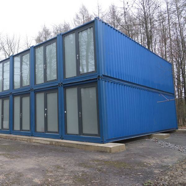 Blaue Container stehen auf einem Platz am Wald.