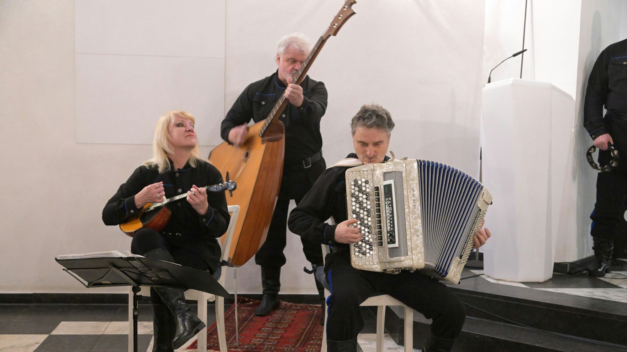 Eine Frau spielt Mandoline, zwei Männer Bassbalalaika und Knopfakkordeon