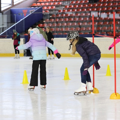 Kinder fahren durch Pylone über die Eisfläche.