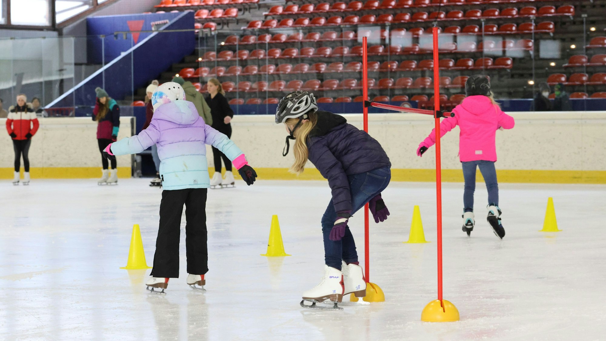 Kinder fahren durch Pylone über die Eisfläche.