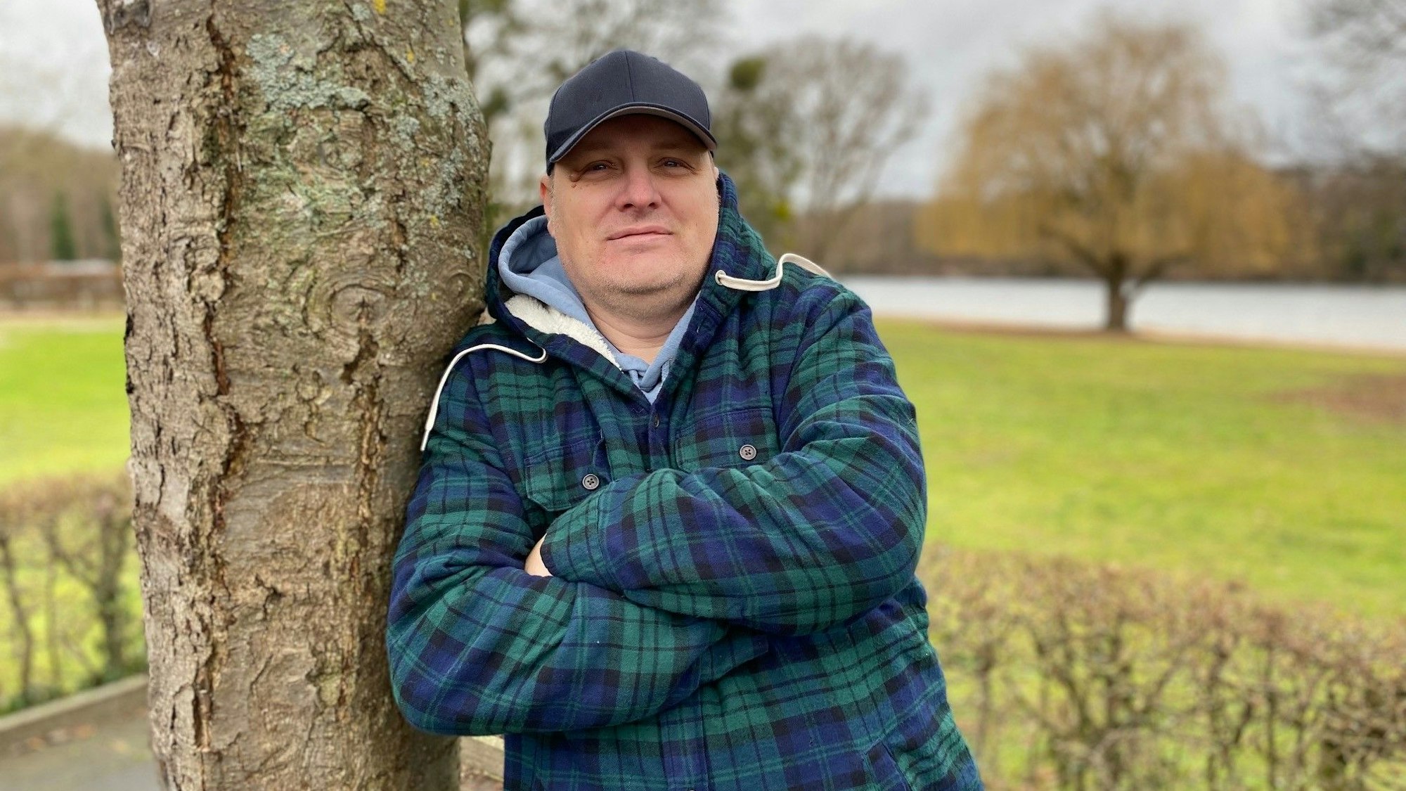 Pächter André Diercks, hier im Januar 2023 in Brühl, lehnt an einem Baum und hat die Arme verschränkt. Er ist der neue Betreiber des Lokals am Heider Bergsee.