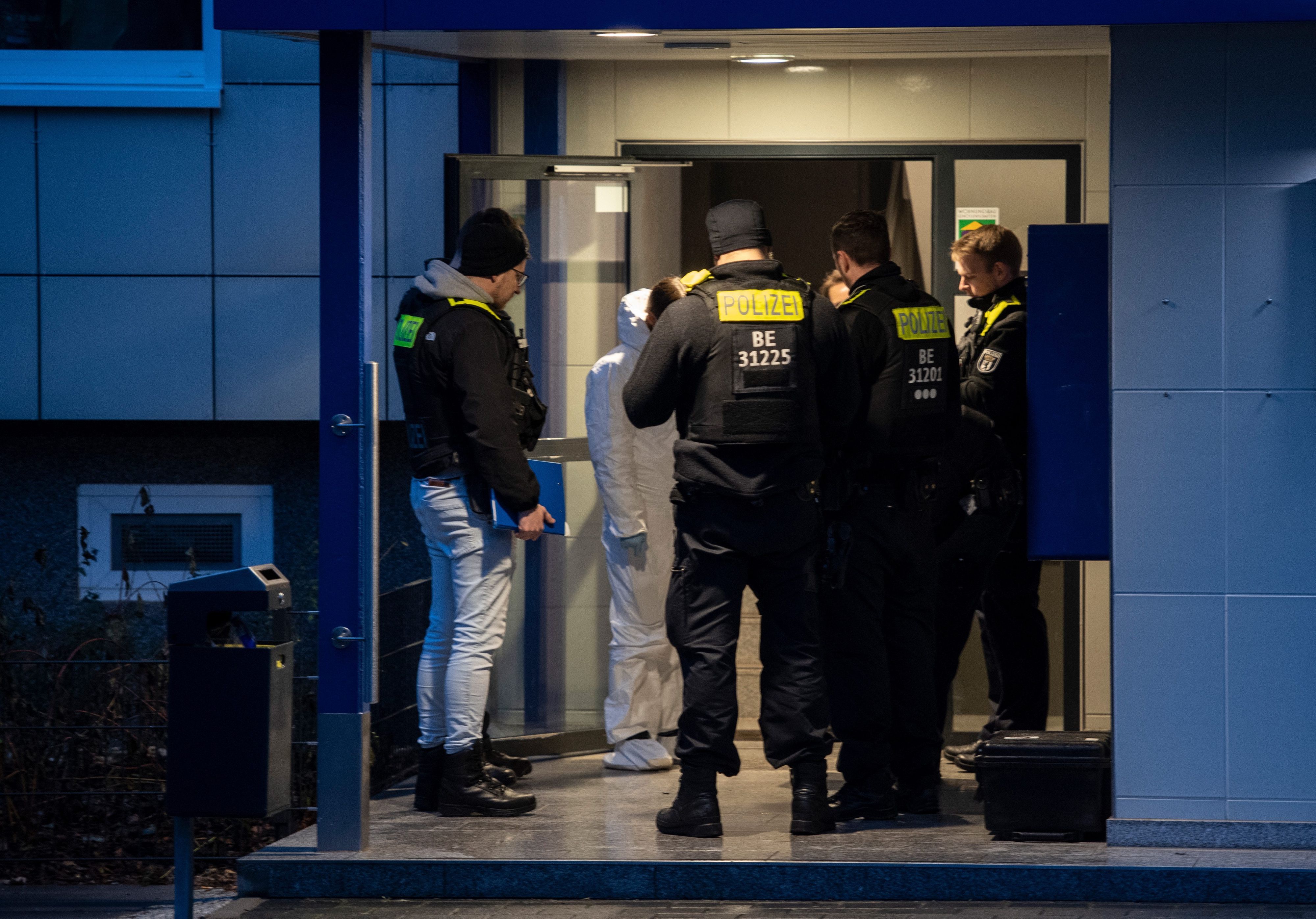 Einsatzkräfte der Polizei stehen an einer Haustür.