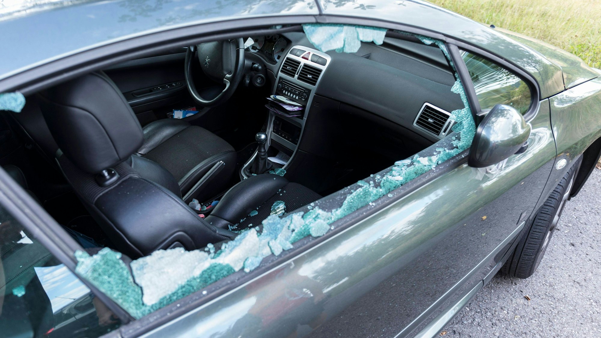 Ein schwarzes Auto mit eingeschlagener Fensterscheibe.