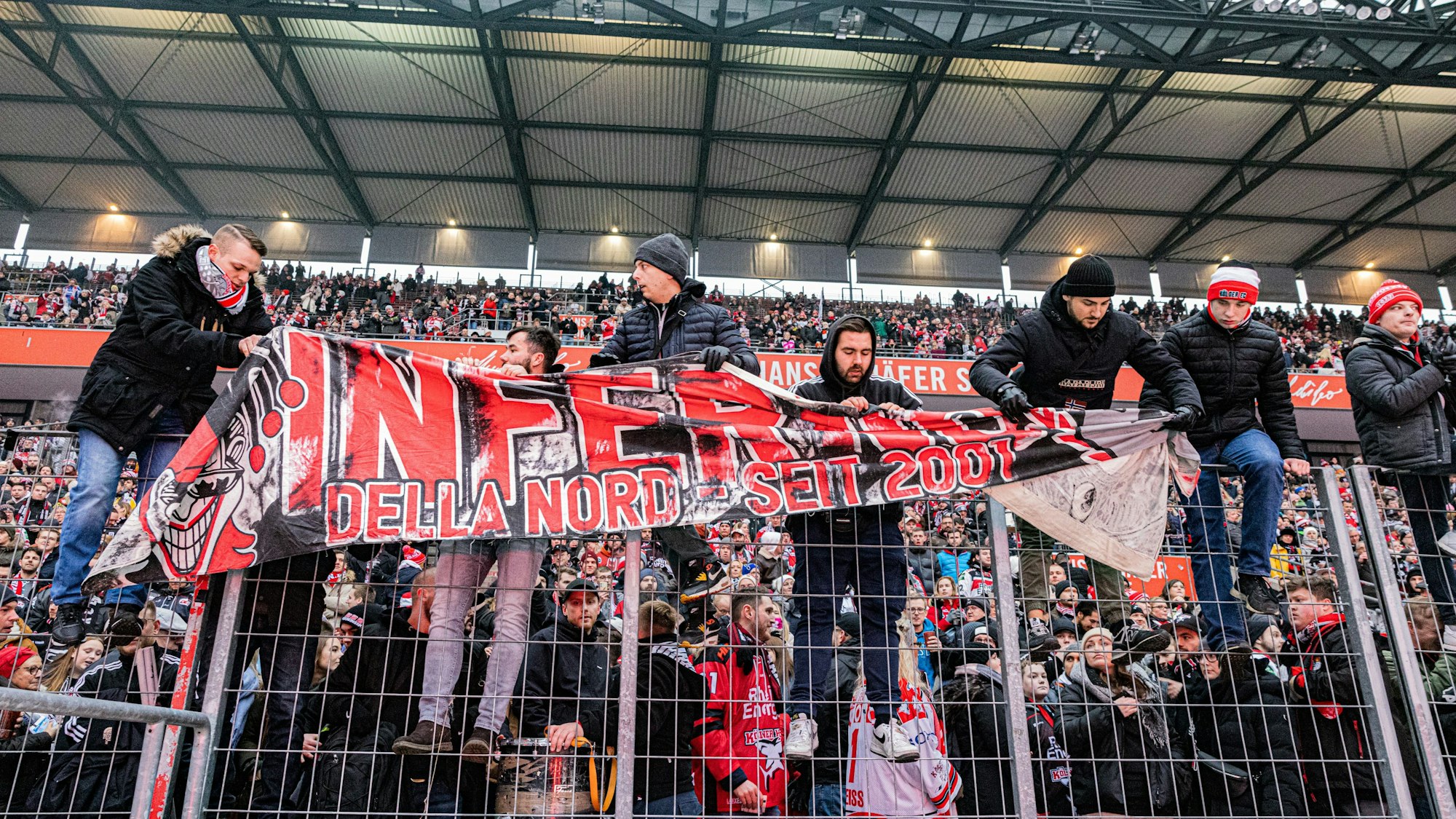 Fans der Kölner Haie befesteigen vor dem Winter Game der Kölner Haie einen Banner am Zaun des Rheinenergie-Stadions.