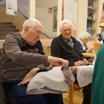 Ein Kind im Sternsinger-Gewand erhält eine Geldspende von einem Senior.