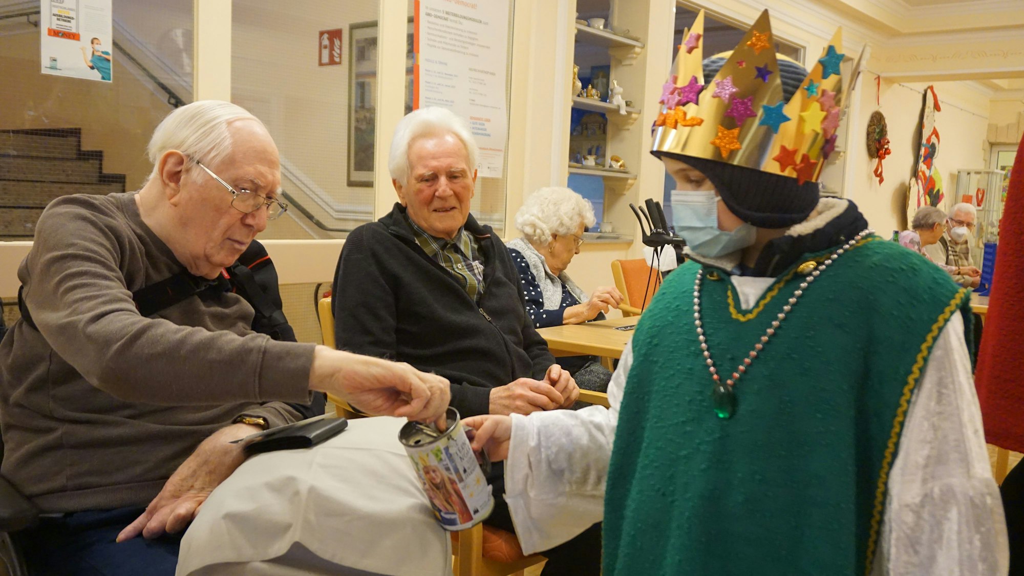 Ein Kind im Sternsinger-Gewand erhält eine Geldspende von einem Senior.