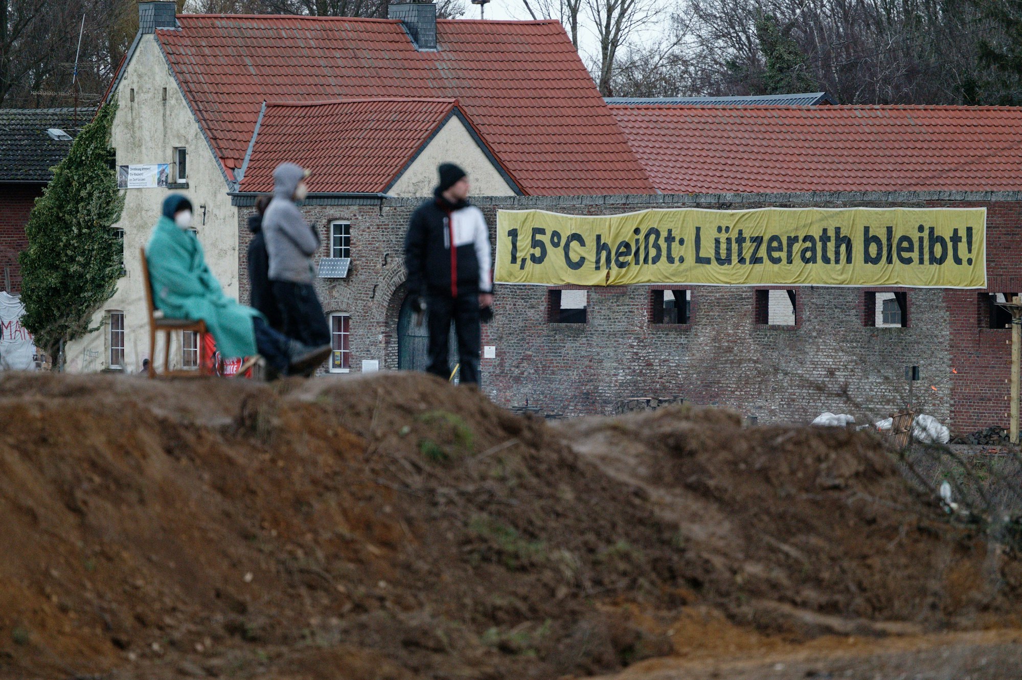 An einem Haus im Dorf Lützerath hängt ein Banner mit der Aufschrift „1,5 Grad Celsius heißt: Lützerath bleibt!“