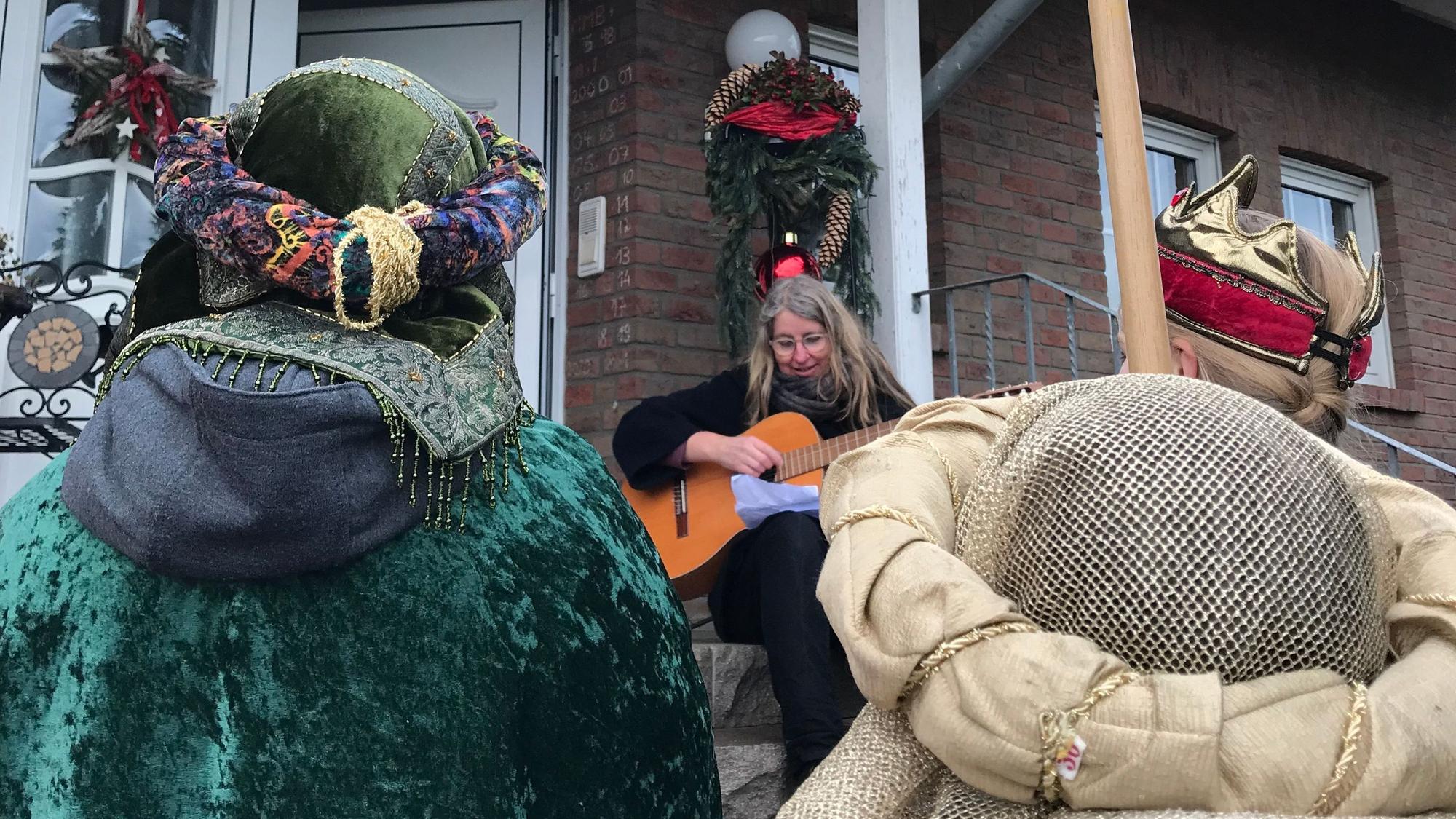 Christa Montenarh mit ihrer Gitarre vor einer Haustür.