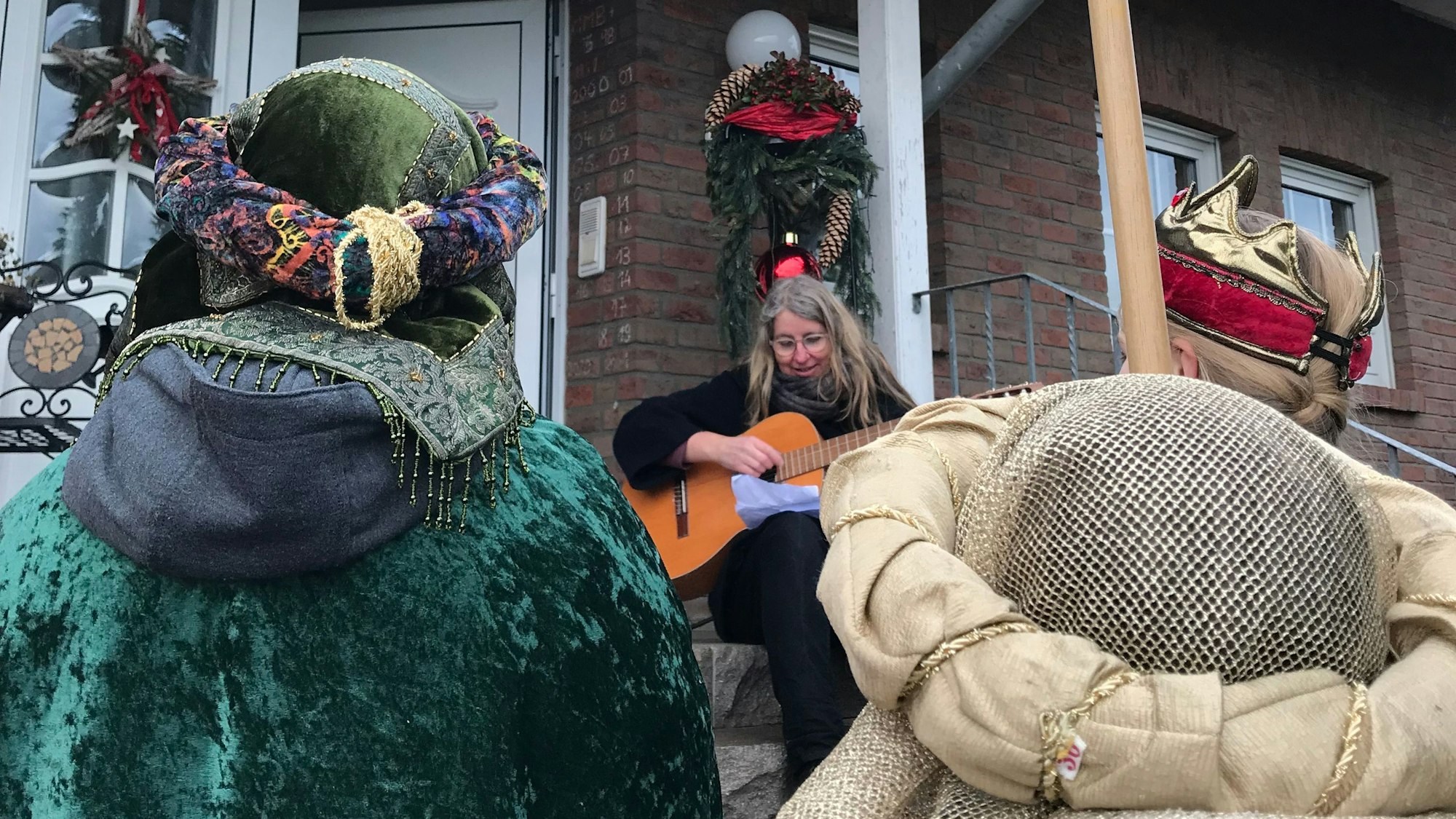 Christa Montenarh mit ihrer Gitarre vor einer Haustür.