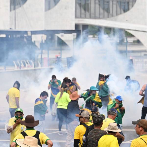Menschen mit Kleidung in den Farben der Flagge Brasiliens stehen in dickem Rauch, einige halten sich Mund und Nase zu.
