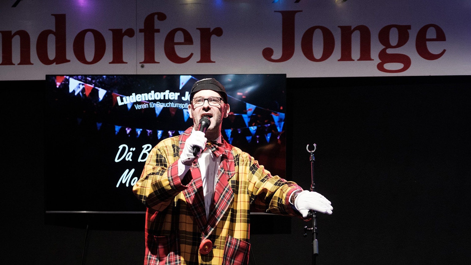 Marc Metzger steht im Clownskostüm bei der Herrensitzung der Ludendorfer Jonge in Morenhoven auf der Bühne