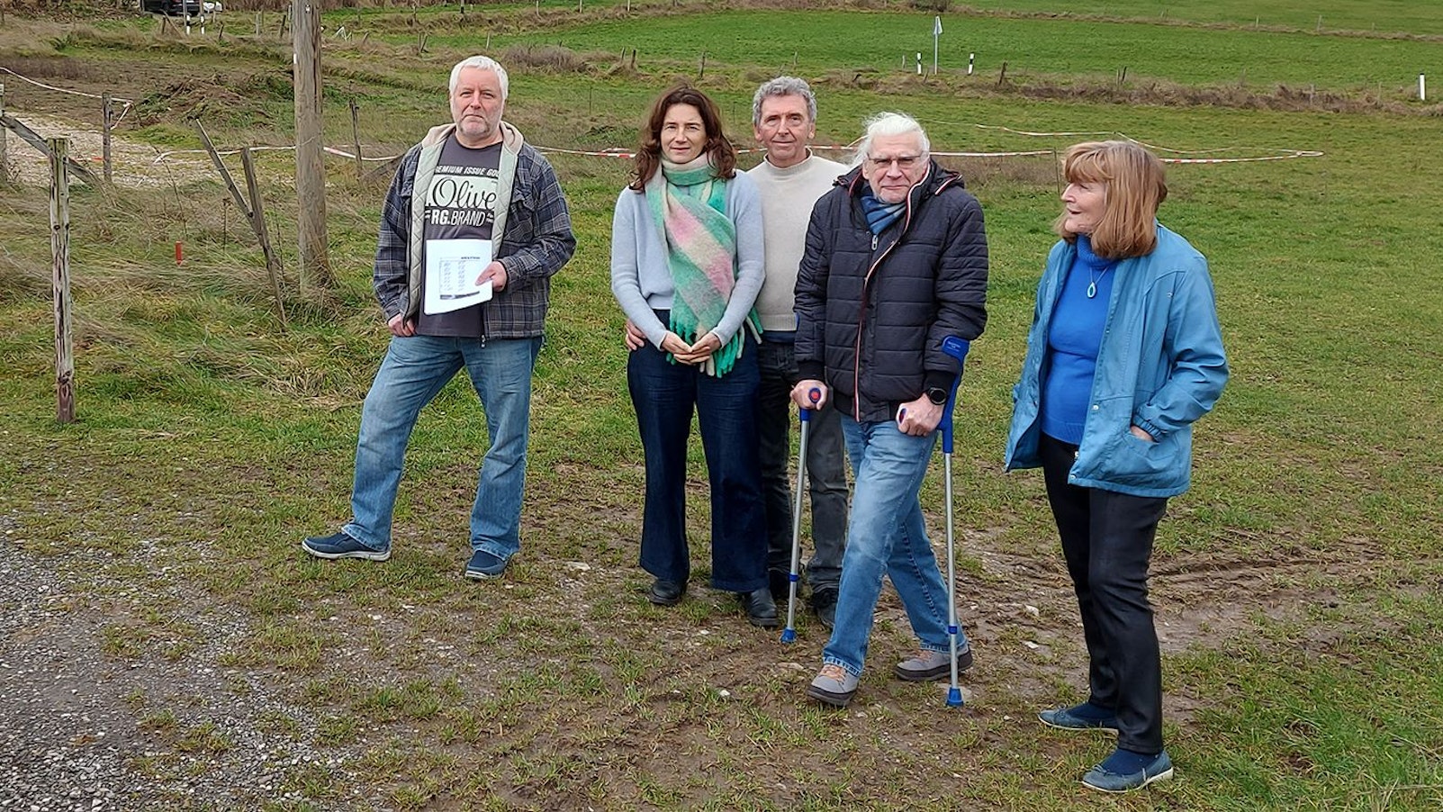 Eine Gruppe verärgerter Anwohner steht auf einer Wiese.