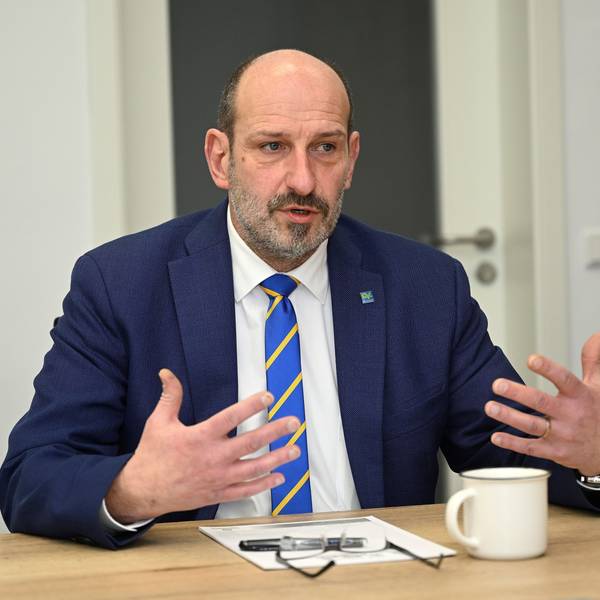 Overaths Bürgermeister Christoph Nicodemus sitzt an einem Tisch und gestikuliert.