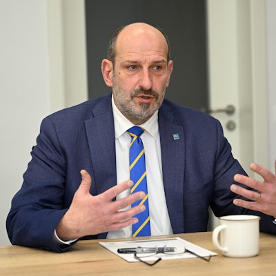 Overaths Bürgermeister Christoph Nicodemus sitzt an einem Tisch und gestikuliert.