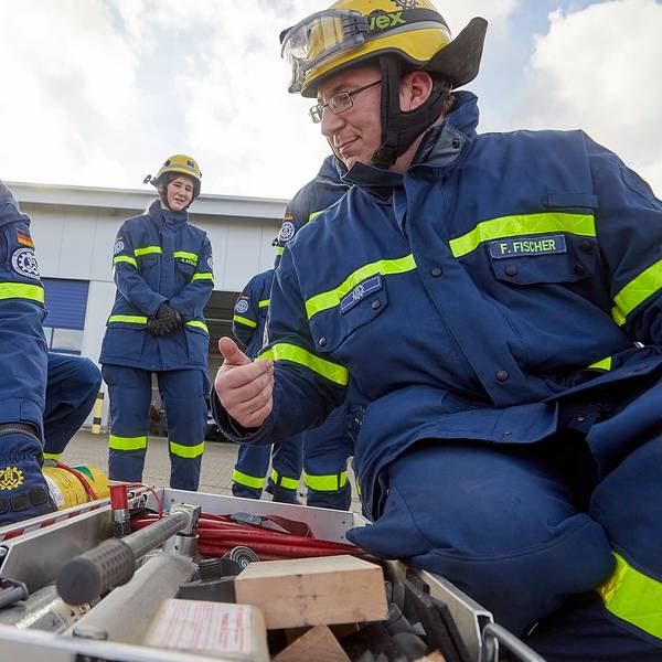 Zwei Männer mit THW-Uniformen hocken vor einer Kiste mit Werkzeugen.